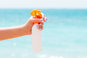 Croped image of woman's hand holding sunblock spray at the beach