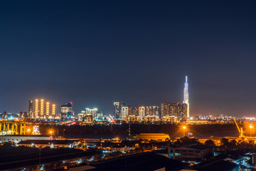 Fototapeta premium Urban night skyline panoramic view of Ho Chi Minh city. Ho Chi Minh City with development buildings, transportation, energy power infrastructure. View from District 7, Saigon. High resolution 