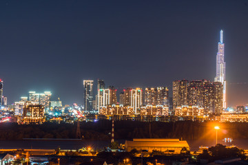 Fototapeta premium Urban night skyline panoramic view of Ho Chi Minh city. Ho Chi Minh City with development buildings, transportation, energy power infrastructure. View from District 7, Saigon. High resolution 