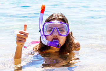 Young woman is wearing diving mask and swimming tube in the sea. Snorkeling equipment