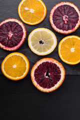 Fototapeta na wymiar Fresh ripe citruses. Lemons, red oranges and oranges on dark stone background. Copy space