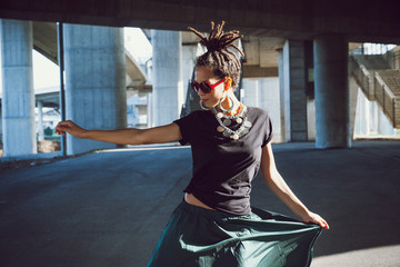 young woman in black t shirt and skirt  with dreadlocks hairstyle sunglasses and lot jewelry...