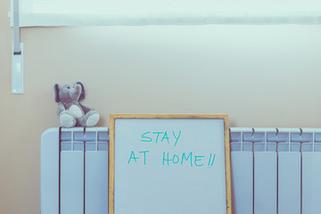 interior of a house with stay at home sign. Window, stove and stuffed animal.