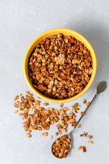 Homemade oatmeal granola bowl with spoon on ligth grey background