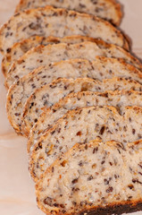 Row of slices of freshly baked, seed bread on the dark wooden boards