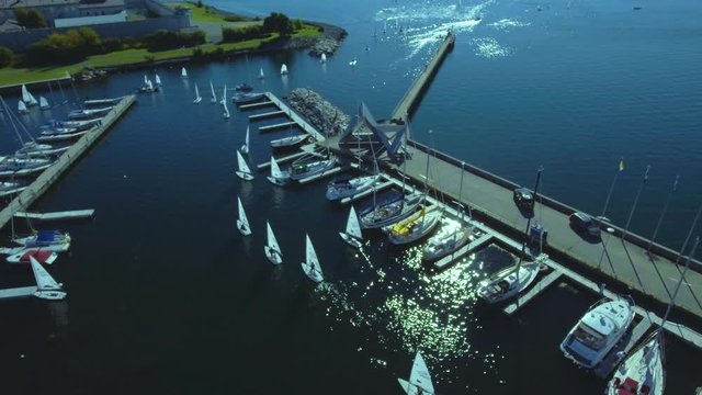 Close aerial view of boats leaving harbour, Beautiful drone view of a port full of boats, water reflection, seagulls flying.