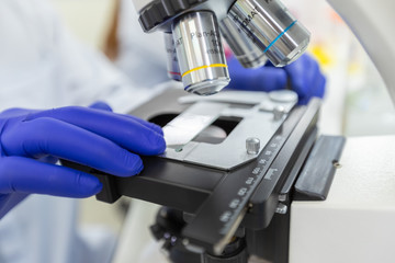 Scientist using microscope with slide sample coronavirus or covid-19, Concept science and Technology