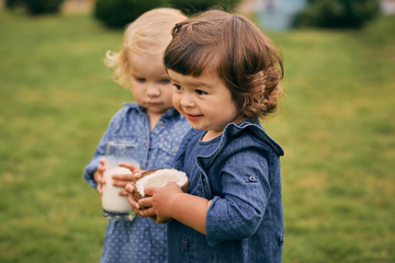 Two little girls holding a glass of coconut milk and coconut in their hands. Healthy and wholesome food.