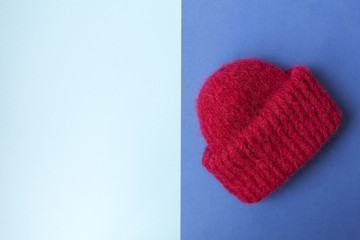 Knitted red hat on the two colors background. Blue background. Knitting courses. Online education. Place for text and design. Copy space. Knitting with love. Quarantine life. Flat lay. Top view. Place
