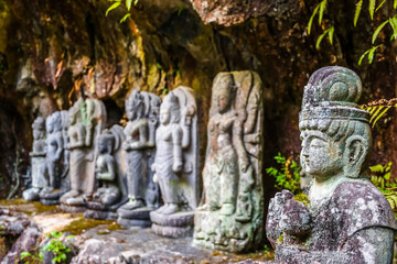 Fototapeta na wymiar Buddhas stone statuettes in the deep wild forest in Japan, holy place