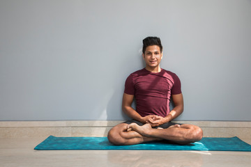 Man sitting on the yoga mat doing exercises. 
