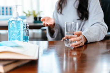 Businesswomen working at home with glass of water takes white round pill in hand.