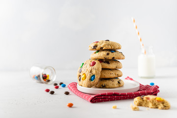 Stack of Homemade vanilla cookies decorated with multi-colored candy drops and a bottle of milk on white background. Side view, copy space. Children menu recipe
