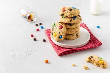 Stack of sweet cookies with colorful candies for children on white background. Side view, copy space. Bakery, confectionery. Recipe