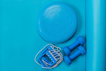 Fitness concept - blue dumbbells, expander and massage cushion on yoga mat
