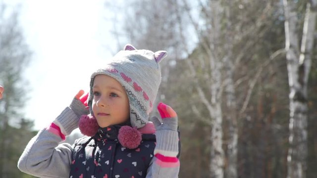 Close up of Mother Helps her Little Daughter to Take Off Protective Medical Mask in a Spring Park. Walking on the Opne Air. Health, Safety, Pandemic Concept