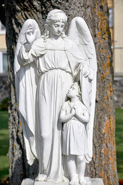 Religious monument of the guardian angel. Monument to the angel made of white stone.