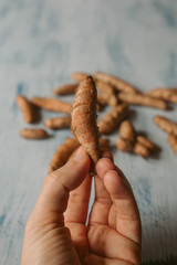 Hand holding turmeric root on wooden background. Close up view. 