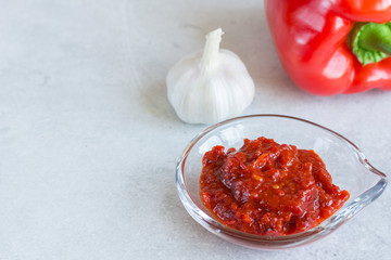 Aivar sauce - a dish of Balkan cuisine in a glass bowl on a table on a light gray background