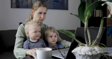 mother working from home. using laptop at desk with kids on her lap