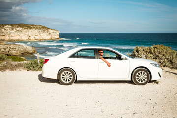 Fototapeta na wymiar Young handsome man in a white car parked on the Australian ocean coast 