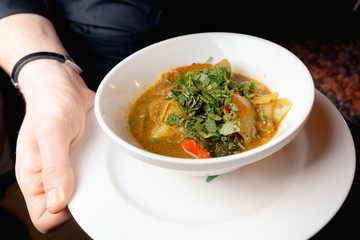 Unidentified man holding a bowl of hot cooked vegetable soup in his hands