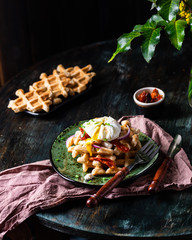 Belgian waffles with egg, arugula, tomatoes and dried meat. Savory waffles. Breakfast concept. poached egg. Sun-dried tomatoes. food in motion. Delicious meal