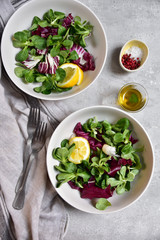 healthy diet salad from radicchio, arugula, valerian leaves with lemon and olive oil in a white bowl on a gray background. vitamin salad recipe. selective focus, copy space