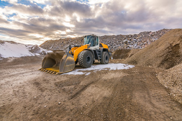 Excavator in a quarry extracting and moving stone for its transformation