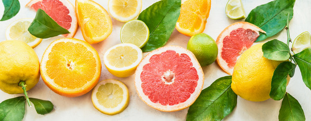 Various citrus fruits background banner with halves, slices and green leaves. Top view. Vitamin C....