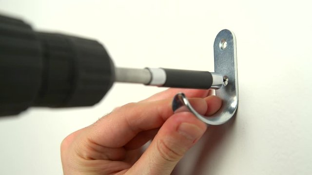 Close-up. Man screwed a metal hook in a sheetrock wall.