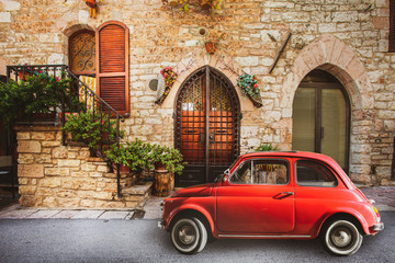 Old vintage italian scene. Small antique red car. Fiat 500. Old Italian house with outside a small subcompact old nostalgia red car, fiat 500. Vintage scene. Assisi, Italy. - obrazy, fototapety, plakaty