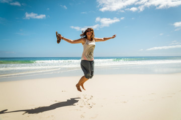 happy young woman jumping on the beach