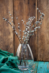 Sprigs of willow in a glass vase. Easter still life. Bouquet on a wooden table. Background for postcards. Simple composition. Spring decor. Rustic style.