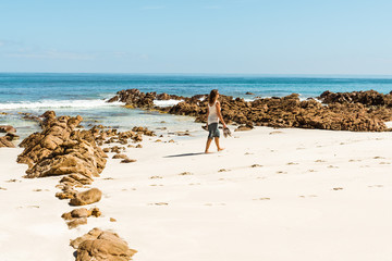 Young European woman walking on a white sandy beach in Australia