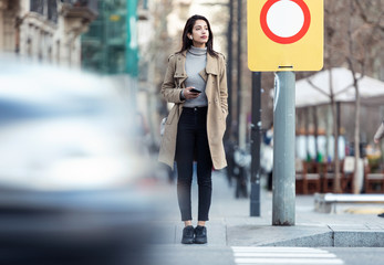 Pretty young woman crossing the street while listen to music with the wireless earphones.