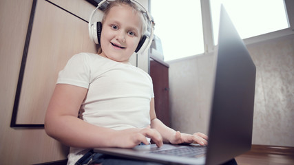 Happy attractive fat smiling girl with a laptop on her lap looks at the camera and smiles. The concept of distance learning during a pandemic and virus.