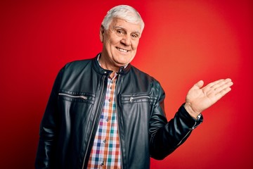 Senior handsome hoary man wearing casual shirt and jacket over isolated red background smiling cheerful presenting and pointing with palm of hand looking at the camera.