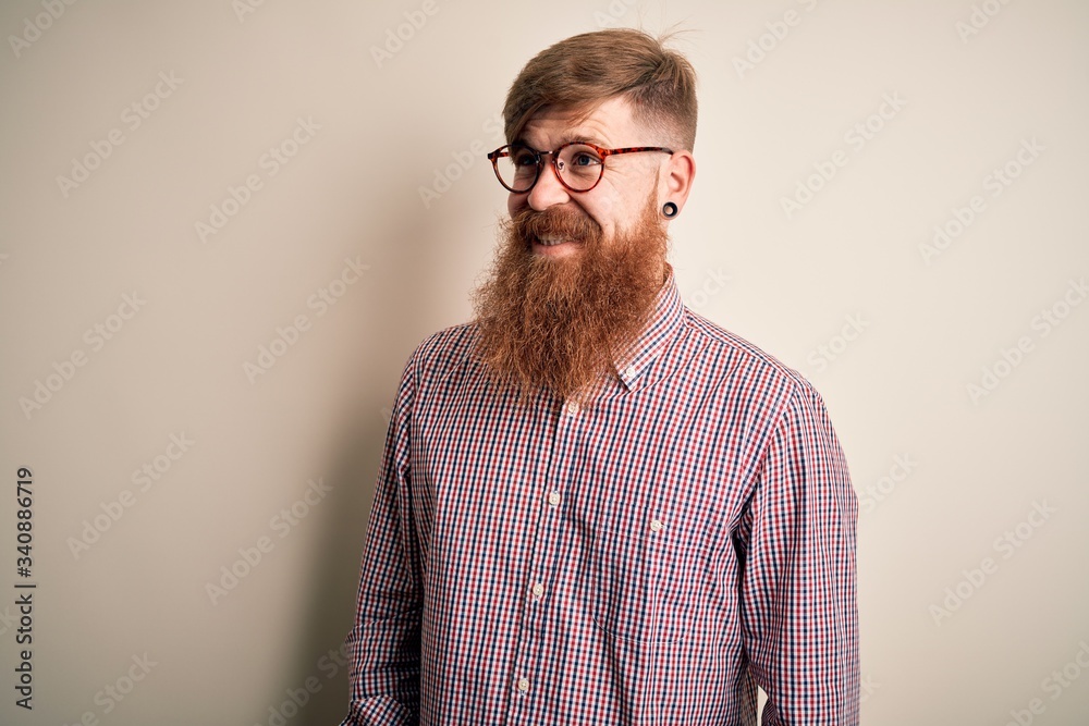 Sticker Handsome Irish redhead business man with beard wearing glasses over isolated background looking away to side with smile on face, natural expression. Laughing confident.