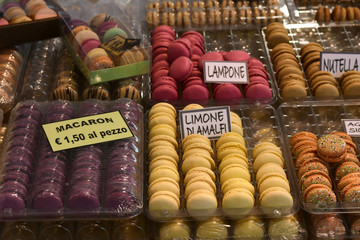 multicolored dessert macarons ( macaroon)  at the local sweet market. white signs in Italian and English indicate the taste of macarons