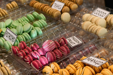multicolored dessert macarons ( macaroon)  at the local sweet market. white signs in Italian and English indicate the taste of macarons