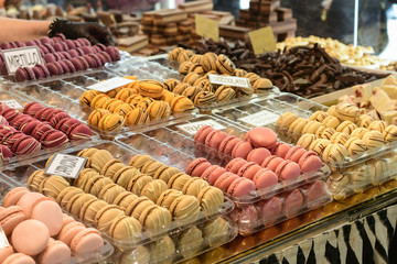 multicolored dessert macarons ( macaroon)  at the local sweet market. white signs in Italian and English indicate the taste of macarons