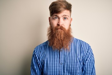 Handsome Irish redhead business man with beard standing over isolated background with serious expression on face. Simple and natural looking at the camera.