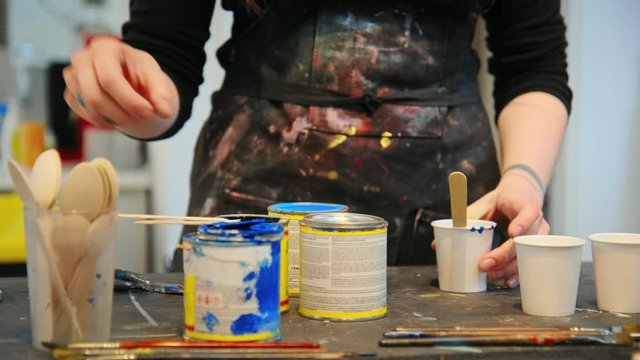 Young woman creative artist in light beautiful workshop mix up paint for new artisan project. Woman during workshop or masterclass to learn new skill