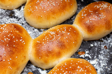 homemade bread hamburger buns with sesame seeds on a baking sheet