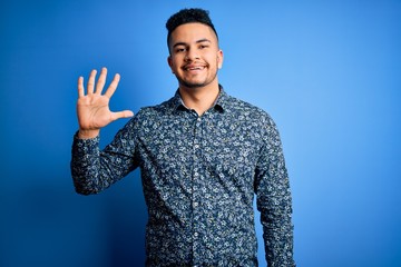 Young handsome man wearing casual shirt standing over isolated blue background showing and pointing...