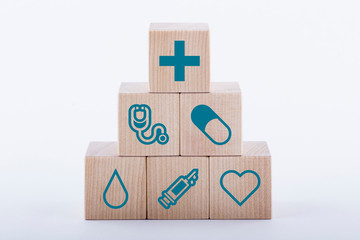 Medical symbols on wooden blocks stacked in a pyramid on white background. Medical and pharmaceutical concept. Medical treatment and public health problems.