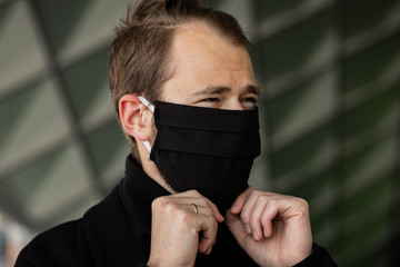Handsome man wearing a mask on the streets of the city. Closeup of a young man in a respirator to protect against infection with influenza virus or coronavirus