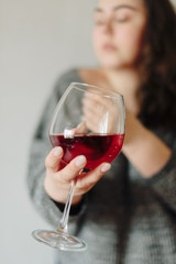 close-up of a girl in a grey sweater with a glass of red wine