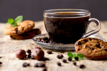 Black coffee in a glass cup with coffee beans. near cookies and hazelnuts